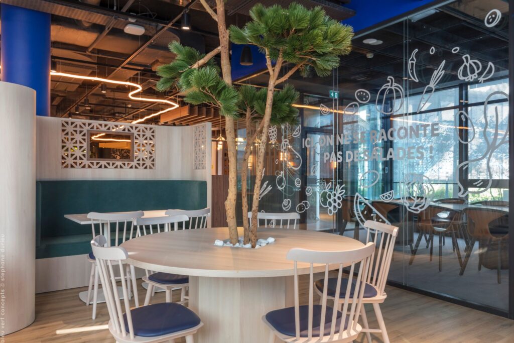 Tables rondes autour d’un arbre et verrière décorée